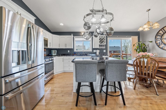 1623 10th St W, West Fargo, ND 58078 - kitchen featuring appliances with stainless steel finishes, a chandelier, white cabinets, light wood-style floors, and a kitchen bar