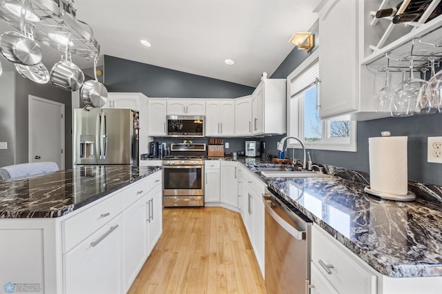 1623 10th St W, West Fargo, ND 58078 - kitchen featuring stainless steel appliances, vaulted ceiling, dark stone counters, light wood finished floors, and white cabinets