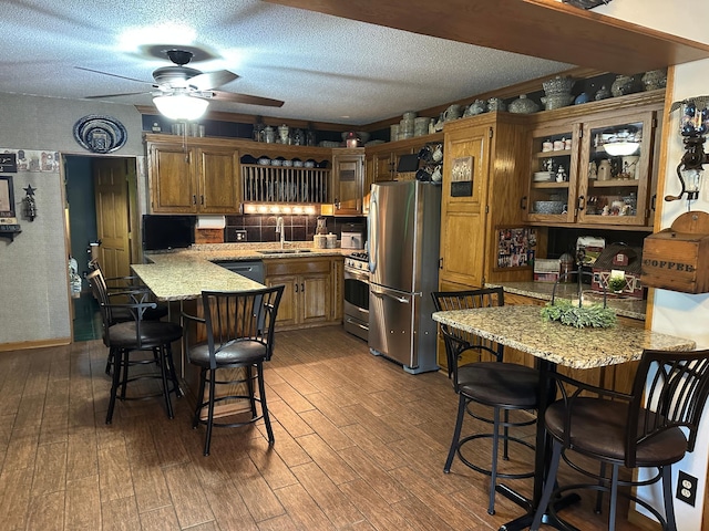 28040 Csah 25, Swede Grove Twp, MN 56243 - kitchen with appliances with stainless steel finishes, a peninsula, a breakfast bar area, wood finished floors, and a textured ceiling