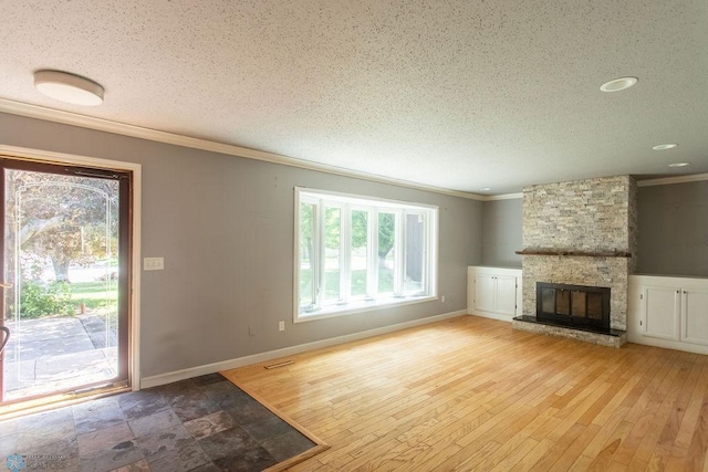 2321 17th Ave S, Fargo, ND 58103 - unfurnished living room featuring healthy amount of natural light, crown molding, a textured ceiling, a stone fireplace, and wood-type flooring
