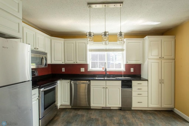 2321 17th Ave S, Fargo, ND 58103 - kitchen with appliances with stainless steel finishes, dark countertops, backsplash, dark wood-style floors, and white cabinetry