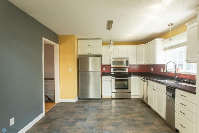2321 17th Ave S, Fargo, ND 58103 - kitchen with appliances with stainless steel finishes, dark countertops, decorative light fixtures, white cabinets, and a textured ceiling