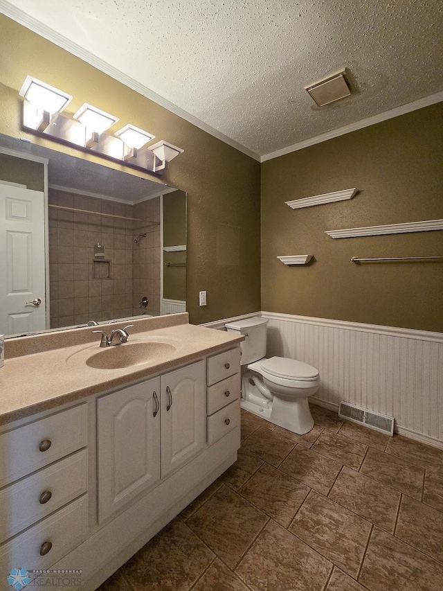 2321 17th Ave S, Fargo, ND 58103 - bathroom featuring crown molding, vanity, a wainscoted wall, a tile shower, and a textured ceiling
