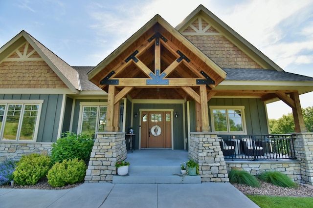 26888 734th Ave, Dassel Twp, MN 55325 - doorway to property featuring board and batten siding, covered porch, stone siding, and roof with shingles