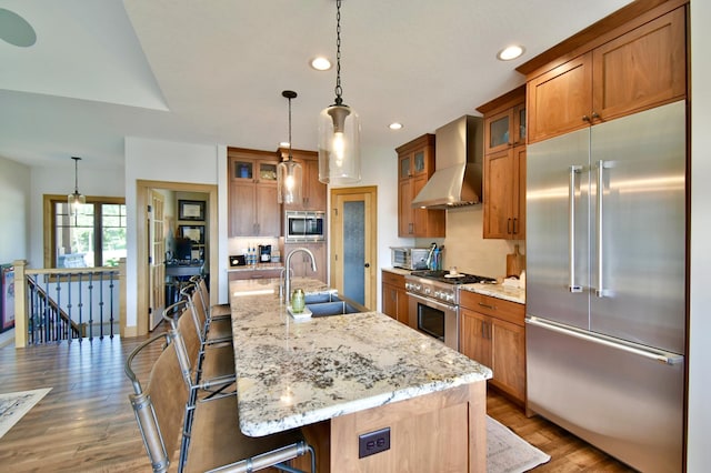 26888 734th Ave, Dassel Twp, MN 55325 - kitchen featuring built in appliances, wall chimney exhaust hood, brown cabinets, wood finished floors, and recessed lighting