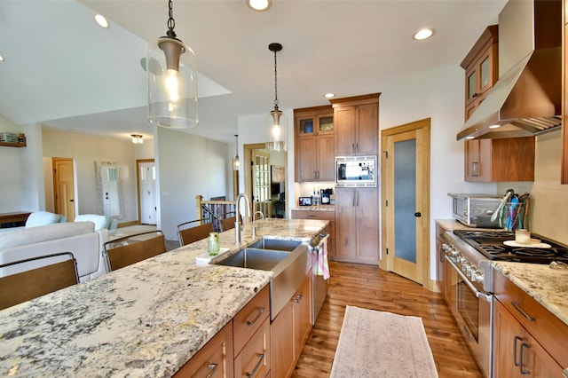26888 734th Ave, Dassel Twp, MN 55325 - kitchen with appliances with stainless steel finishes, wall chimney exhaust hood, brown cabinetry, light wood finished floors, and light stone countertops