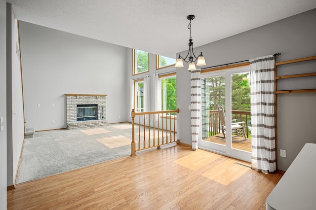 8798 Fountain Ln N, Maple Grove, MN 55311 - unfurnished dining area with a chandelier, wood finished floors, a fireplace, and a textured ceiling