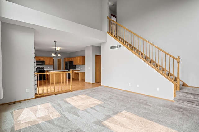 8798 Fountain Ln N, Maple Grove, MN 55311 - unfurnished living room with light colored carpet, a chandelier, stairs, and a towering ceiling