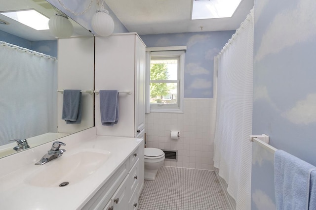 4901 99th St, Bloomington, MN 55437 - bathroom with vanity, tile walls, tile patterned floors, a skylight, and a wainscoted wall