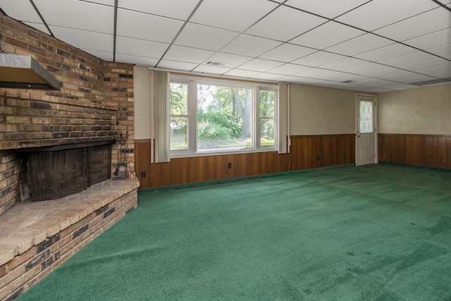 4901 99th St, Bloomington, MN 55437 - unfurnished living room featuring a wainscoted wall, a brick fireplace, carpet, wood walls, and a drop ceiling