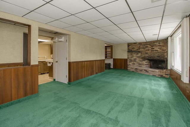 4901 99th St, Bloomington, MN 55437 - unfurnished living room with a wainscoted wall, wood walls, a fireplace, a paneled ceiling, and light colored carpet