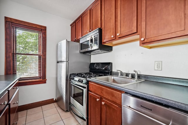 1812 Clinton Ave Unit 203, Minneapolis, MN 55404 - kitchen featuring stainless steel appliances, dark countertops, light tile patterned floors, and brown cabinets