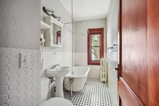 1812 Clinton Ave Unit 203, Minneapolis, MN 55404 - bathroom featuring radiator heating unit, a freestanding bath, tile walls, wainscoting, and a shower