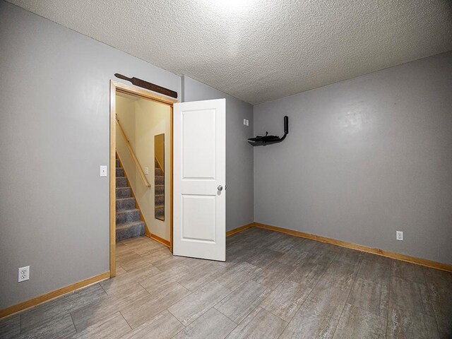 906 New Century Blvd S, Maplewood, MN 55119 - below grade area with light wood finished floors, stairway, and a textured ceiling