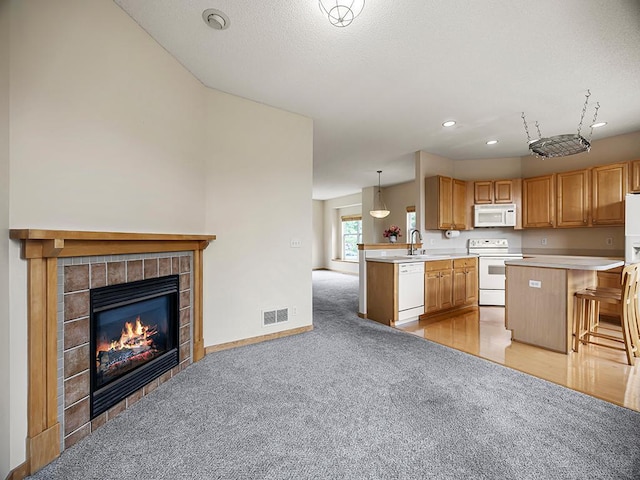 906 New Century Blvd S, Maplewood, MN 55119 - kitchen featuring white appliances, a peninsula, light colored carpet, a kitchen breakfast bar, and light countertops