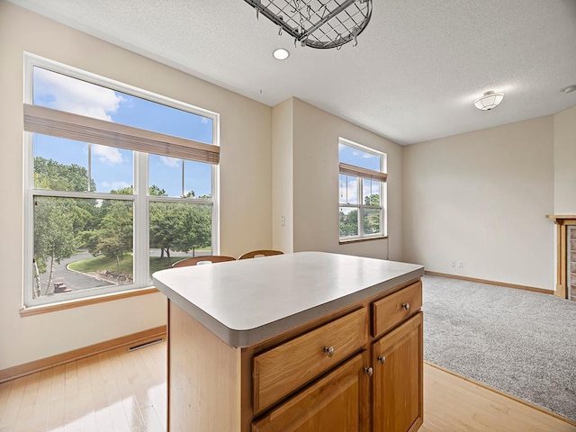 906 New Century Blvd S, Maplewood, MN 55119 - kitchen featuring a textured ceiling, open floor plan, a kitchen island, light wood finished floors, and brown cabinetry