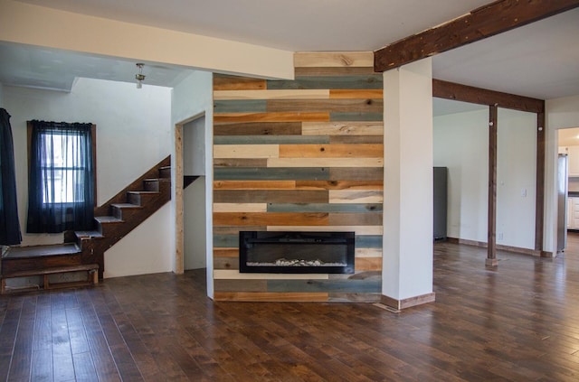 305 2nd Ave SE, Plainview, MN 55964 - unfurnished living room featuring wood walls, wood-type flooring, a glass covered fireplace, stairs, and beamed ceiling