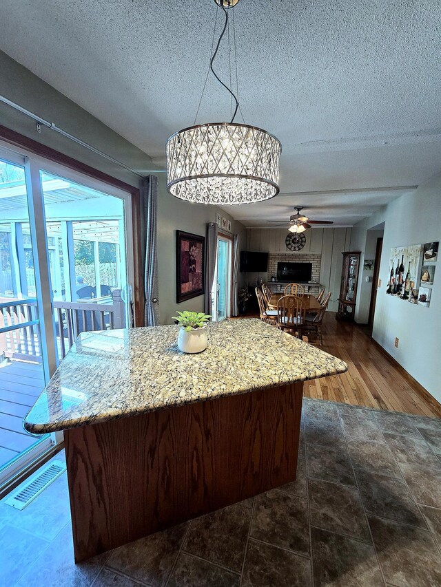 8047 Ingleside Ave S, Cottage Grove, MN 55016 - kitchen with a textured ceiling, a ceiling fan, a kitchen island, light stone counters, and pendant lighting