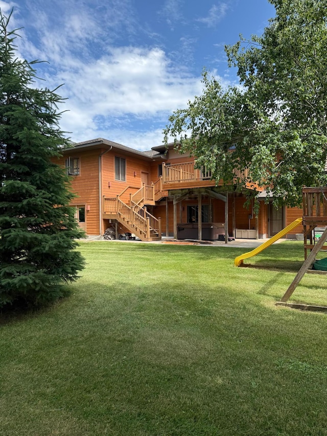 1905 Abby Rd, Cumberland, WI 54829 - view of green lawn with stairway, a hot tub, a wooden deck, and a playground