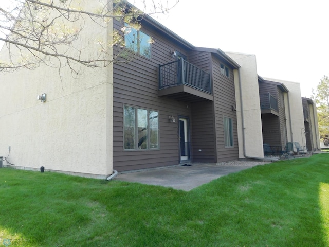 42710 County Highway 56 Unit 101, Toad Lake Twp, MN 56544 - back of property with a balcony, a lawn, a patio area, and stucco siding