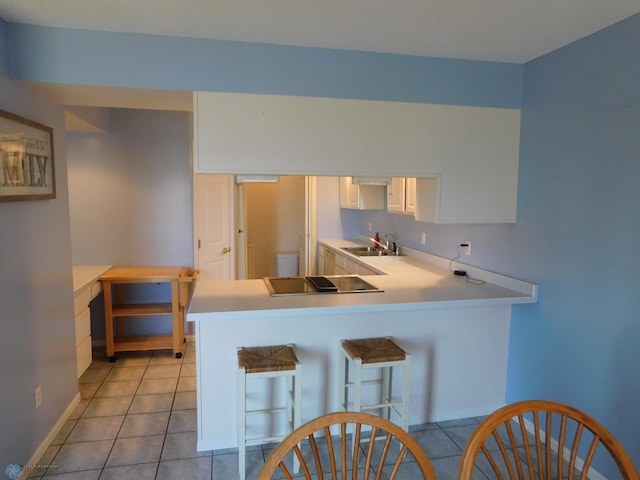42710 County Highway 56 Unit 101, Toad Lake Twp, MN 56544 - kitchen featuring black electric stovetop, light tile patterned floors, white cabinets, a peninsula, and light countertops