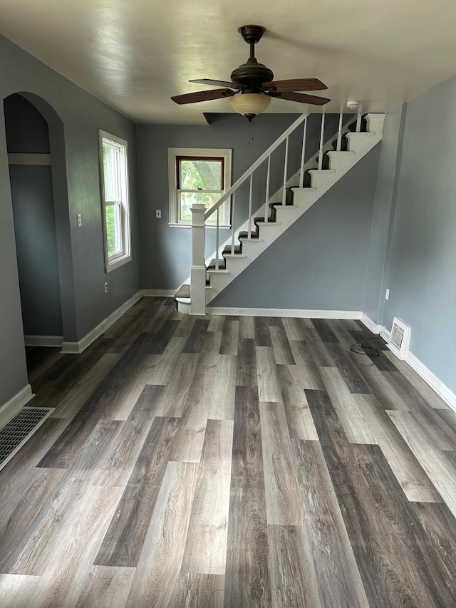 551 Center St, Tracy, MN 56175 - unfurnished living room with arched walkways, stairway, a ceiling fan, and wood finished floors
