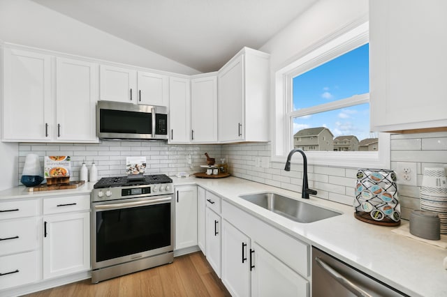 26622 8th St W, Zimmerman, MN 55398 - kitchen featuring appliances with stainless steel finishes, vaulted ceiling, light countertops, white cabinets, and backsplash