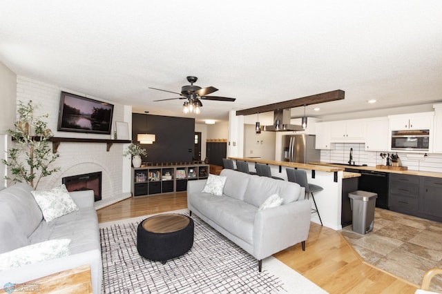 25 Birch Ln S, Fargo, ND 58103 - living room featuring a ceiling fan, a brick fireplace, light wood-type flooring, a textured ceiling, and recessed lighting