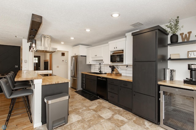 25 Birch Ln S, Fargo, ND 58103 - kitchen featuring butcher block counters, beverage cooler, black appliances, a kitchen breakfast bar, and white cabinetry
