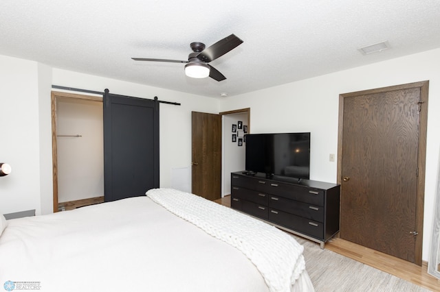 25 Birch Ln S, Fargo, ND 58103 - bedroom with light wood-type flooring, a barn door, and ceiling fan