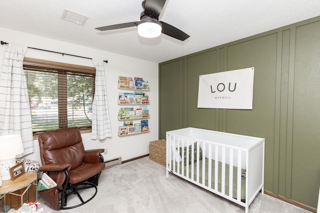 25 Birch Ln S, Fargo, ND 58103 - carpeted bedroom with a baseboard heating unit, a crib, a decorative wall, a ceiling fan, and a textured ceiling