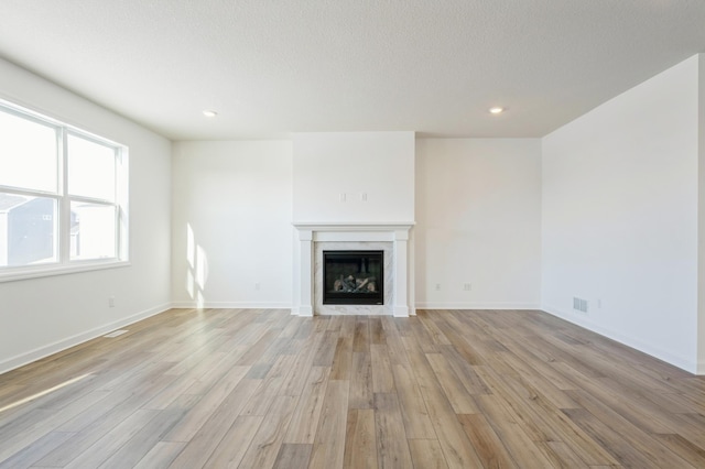 8362 Lander Ave NE, Otsego, MN 55330 - unfurnished living room featuring light wood-style flooring, a fireplace, recessed lighting, and a textured ceiling