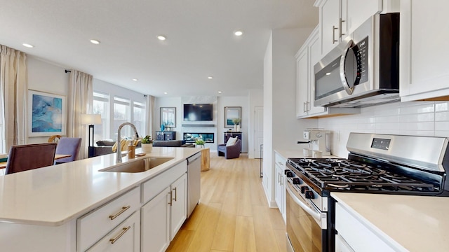 7593 Norway Ln, Lino Lakes, MN 55038 - kitchen with stainless steel appliances, decorative backsplash, open floor plan, light wood-style floors, and light countertops