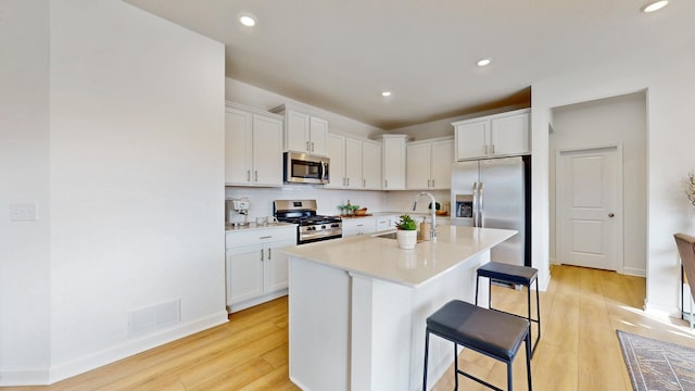 7593 Norway Ln, Lino Lakes, MN 55038 - kitchen featuring stainless steel appliances, a breakfast bar, light wood-type flooring, white cabinetry, and recessed lighting