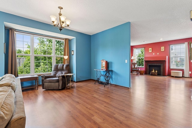 5214 Scott Ct, Robbinsdale, MN 55422 - living area featuring a chandelier, wood finished floors, a fireplace with flush hearth, and a textured ceiling