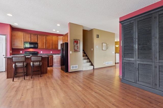 5214 Scott Ct, Robbinsdale, MN 55422 - kitchen featuring black appliances, light wood-style flooring, a kitchen island, a breakfast bar area, and recessed lighting