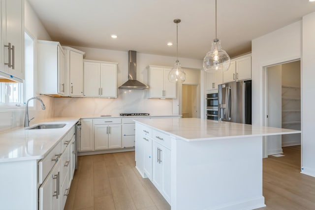6722 Tamarack Ln, Corcoran, MN 55340 - kitchen featuring appliances with stainless steel finishes, wall chimney range hood, light wood-style flooring, a center island, and recessed lighting