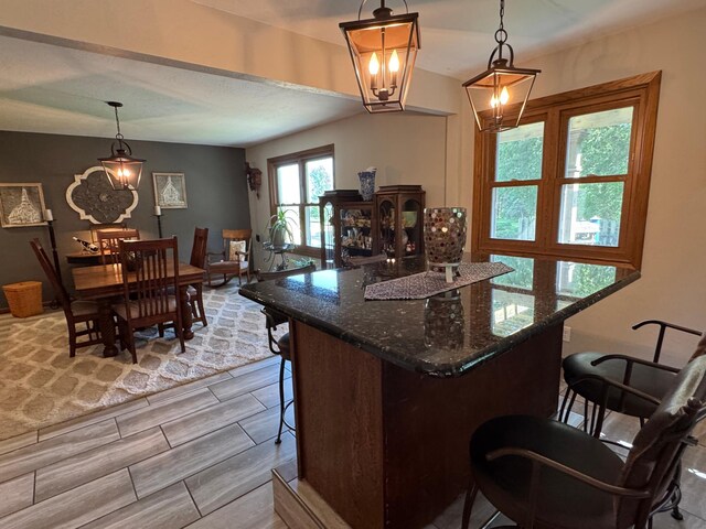 715 250th Ave, Fairmont, MN 56031 - kitchen with a breakfast bar, dark stone counters, a center island, decorative light fixtures, and wood tiled floors
