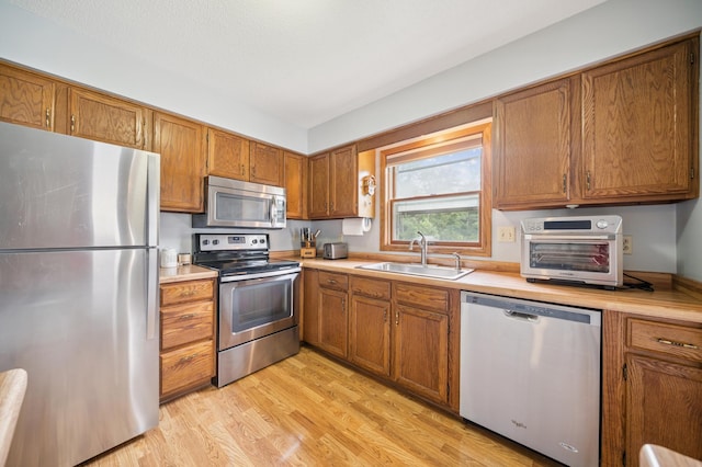 2227 3rd St SW, Rochester, MN 55902 - kitchen with stainless steel appliances, brown cabinetry, light countertops, and light wood finished floors