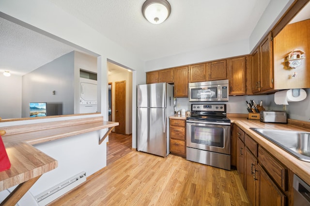 2227 3rd St SW, Rochester, MN 55902 - kitchen with stainless steel appliances, estacked washer and dryer, baseboard heating, brown cabinetry, and light countertops