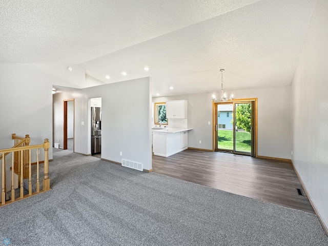 3337 Monroe St S, Fargo, ND 58104 - living room with a chandelier, dark colored carpet, vaulted ceiling, a textured ceiling, and dark wood-type flooring