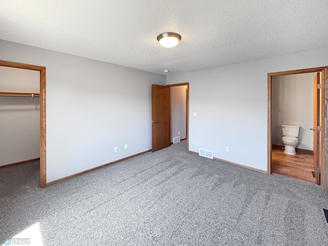 3337 Monroe St S, Fargo, ND 58104 - unfurnished bedroom with carpet, a spacious closet, a textured ceiling, a closet, and connected bathroom