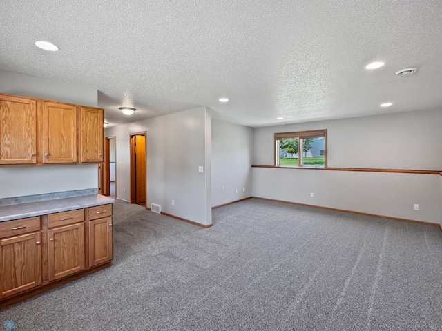 3337 Monroe St S, Fargo, ND 58104 - kitchen featuring a textured ceiling, recessed lighting, carpet floors, brown cabinetry, and light countertops