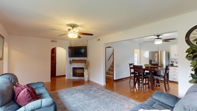 711 5th Ave SW, Austin, MN 55912 - living area featuring ceiling fan, arched walkways, a large fireplace, and light wood-style floors