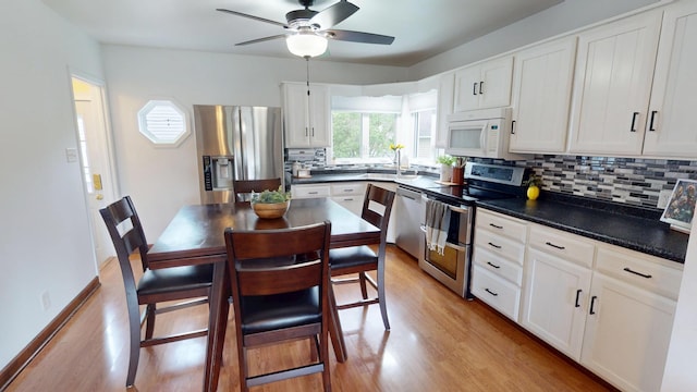 711 5th Ave SW, Austin, MN 55912 - kitchen with stainless steel appliances, light wood-style floors, backsplash, white cabinets, and a ceiling fan