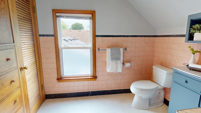 711 5th Ave SW, Austin, MN 55912 - bathroom with vanity, vaulted ceiling, tile walls, wainscoting, and a closet