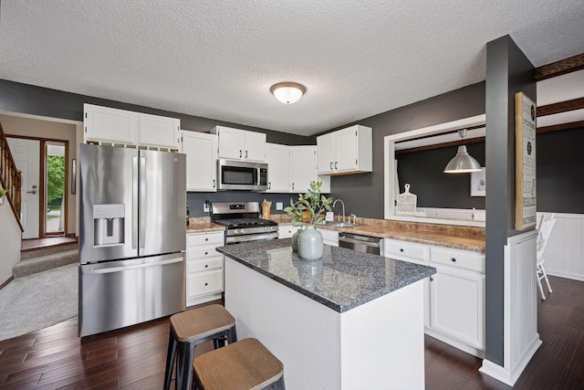 420 Pleasant Crest Cir, Annandale, MN 55302 - kitchen featuring appliances with stainless steel finishes, white cabinets, dark wood-style flooring, a kitchen island, and a textured ceiling