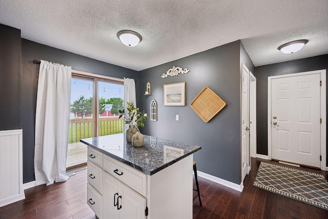 420 Pleasant Crest Cir, Annandale, MN 55302 - kitchen with dark wood finished floors, white cabinets, a breakfast bar area, a center island, and a textured ceiling