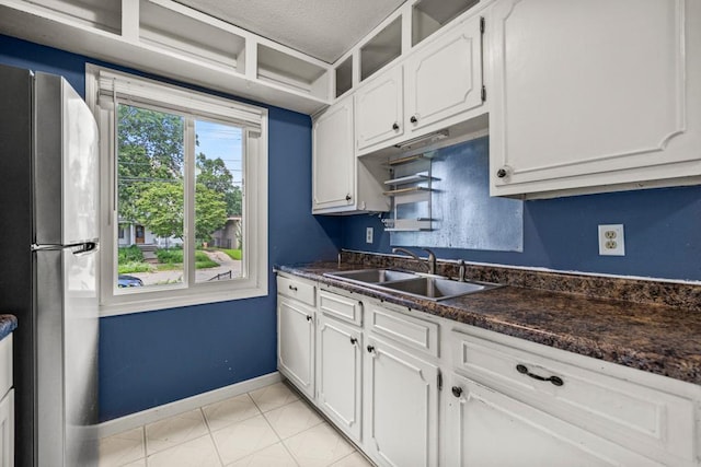 2717 22nd St, Minneapolis, MN 55406 - kitchen with freestanding refrigerator, dark countertops, white cabinets, light tile patterned floors, and a textured ceiling