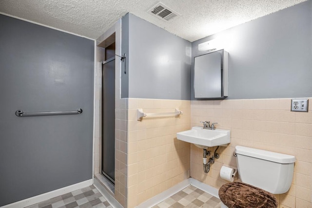 2717 22nd St, Minneapolis, MN 55406 - full bathroom featuring a textured ceiling, a stall shower, tile patterned floors, tile walls, and a wainscoted wall
